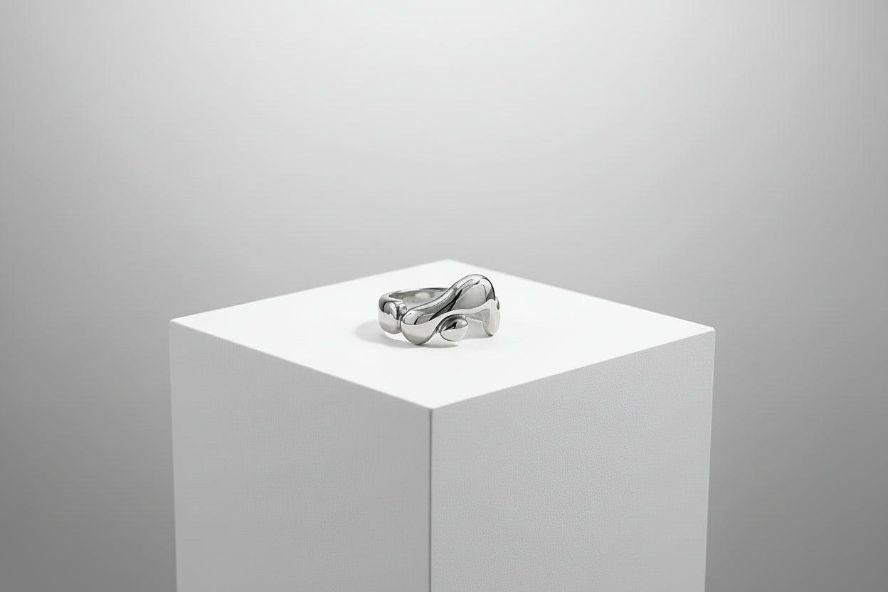 Silver ring on a white pedestal against a gray background