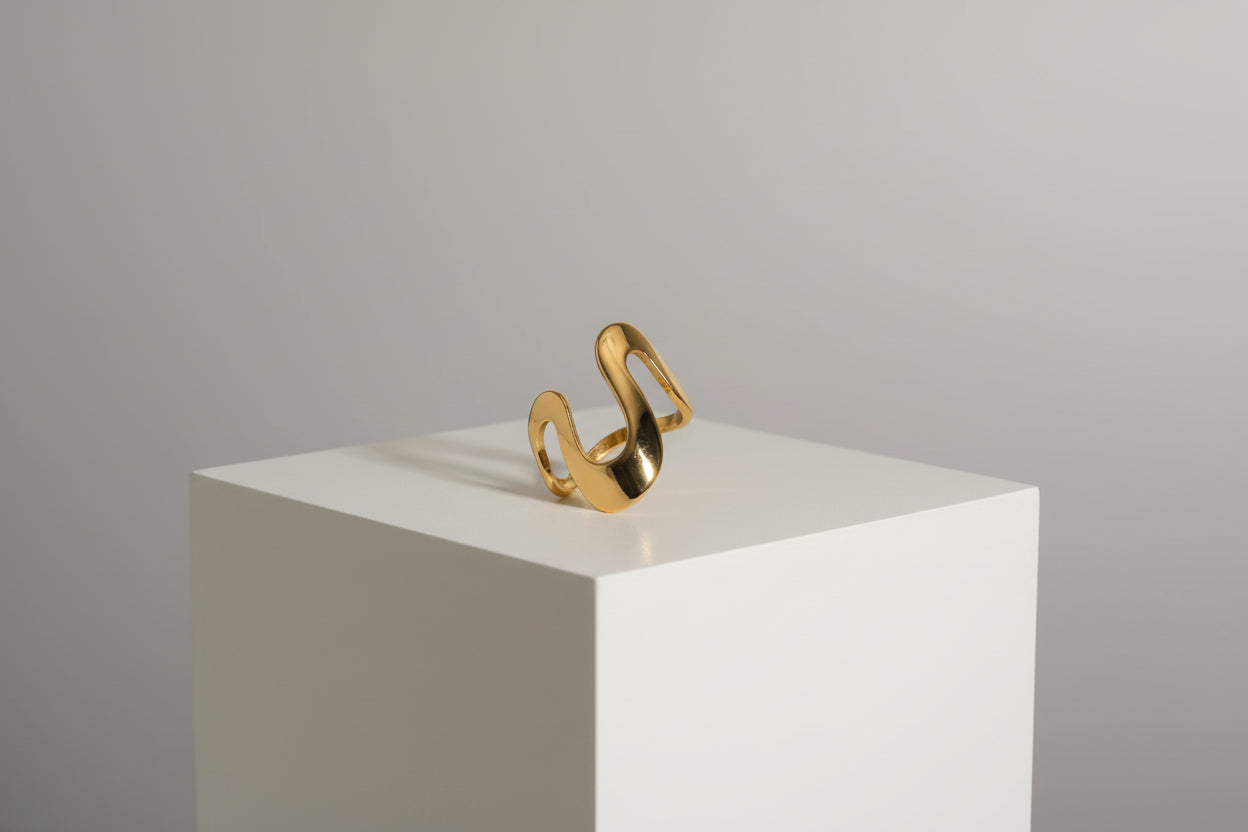 Ein vergoldeter Edelstahlring mit geometrischem Design, präsentiert auf weißem Untergrund.