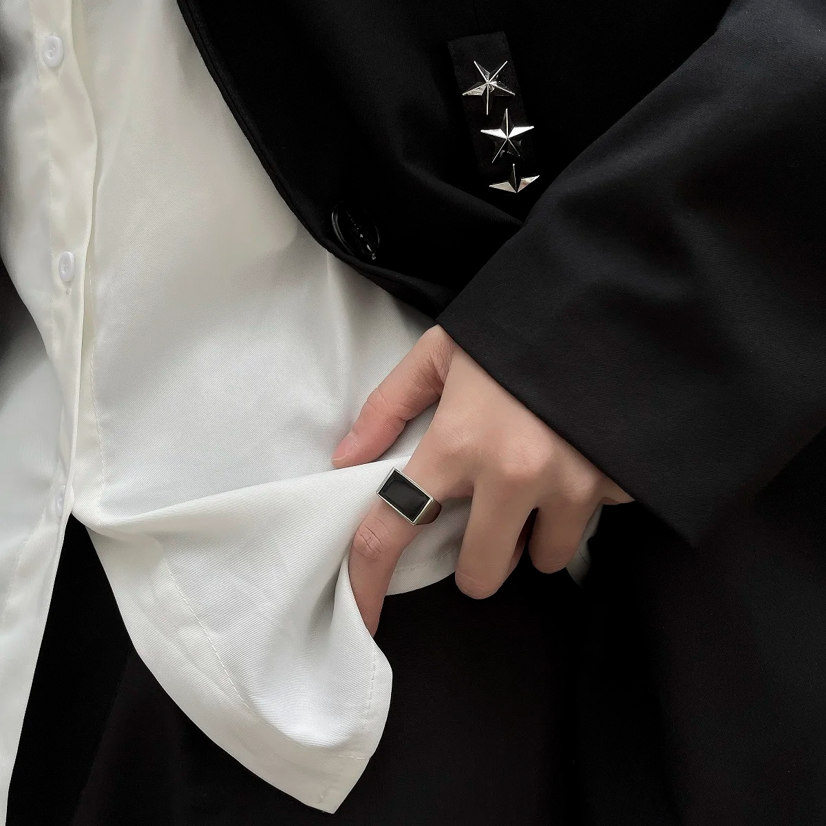 Close-up of a person wearing a black coat with a star emblem and a white shirt.