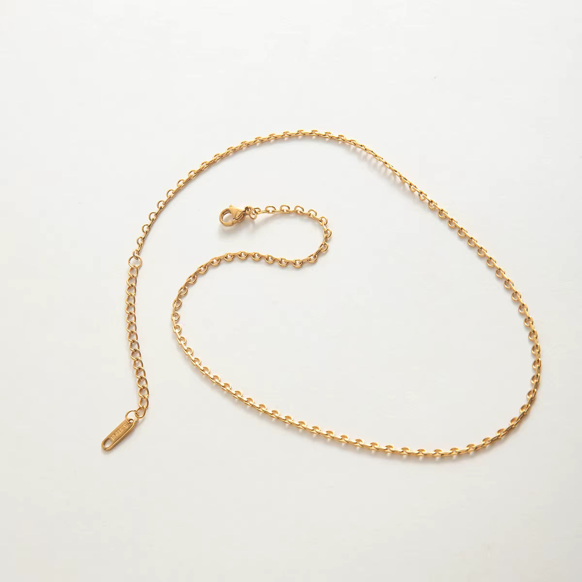 Gold chain necklace on a light gray background