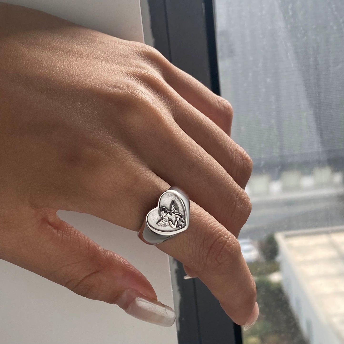Heart-shaped ring on a finger with a blurred background