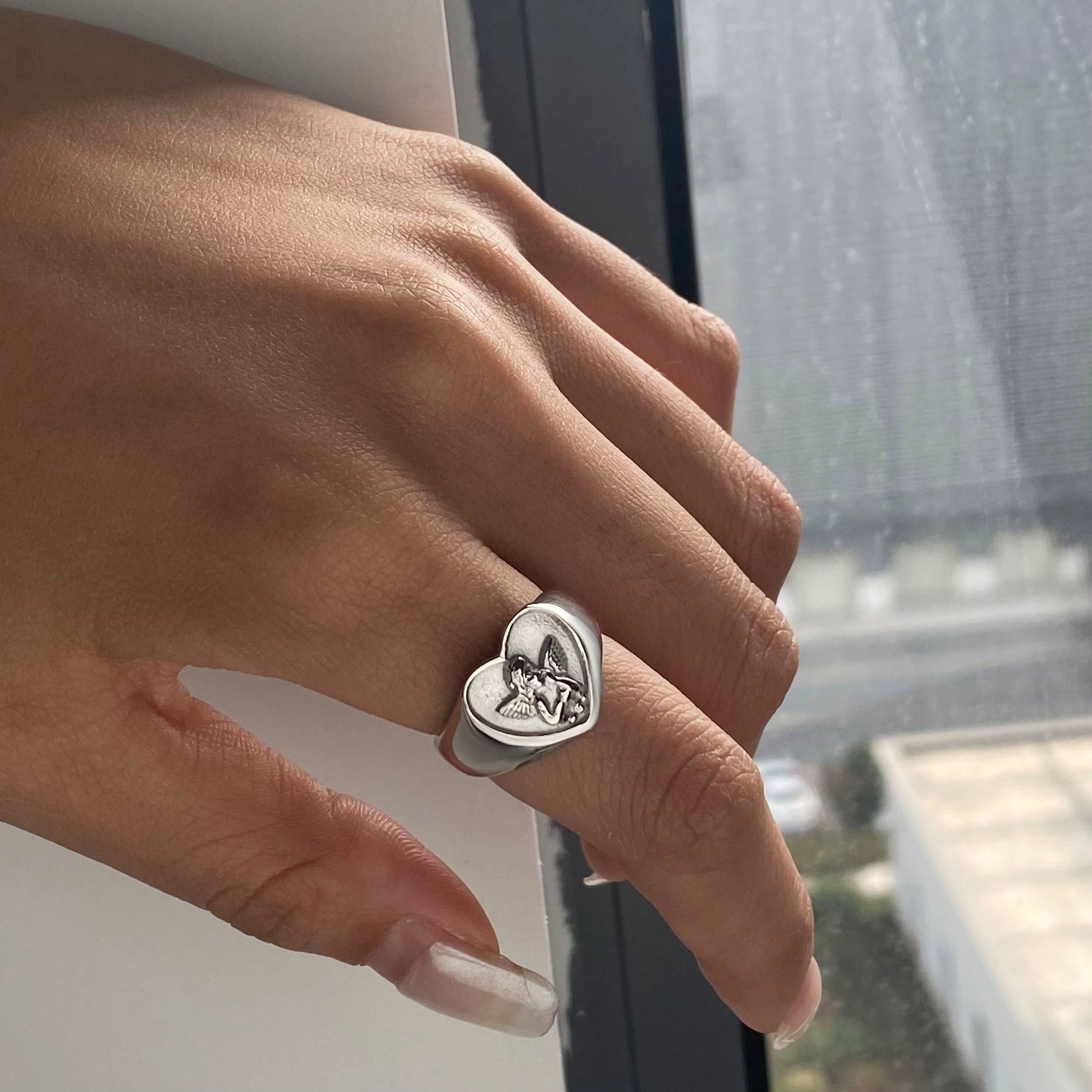 Heart-shaped ring on a finger with a blurred background