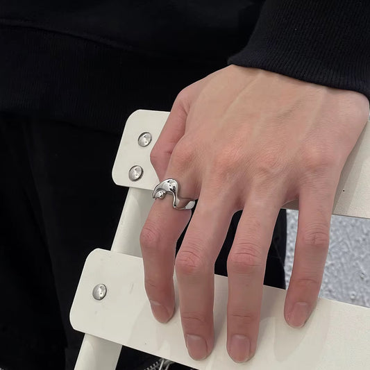 Hand wearing a silver ring on a white chair with a black background