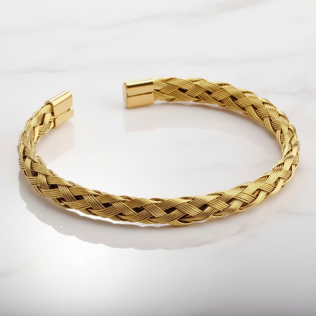 Gold braided bracelet on a light gray background