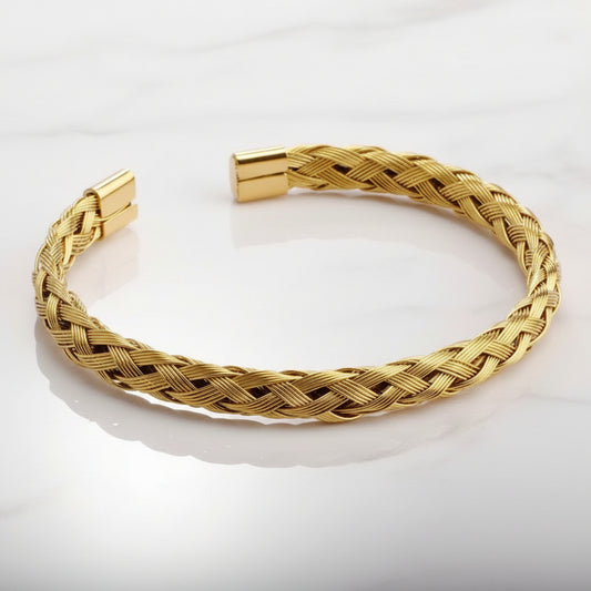 Gold braided bracelet on a light gray background