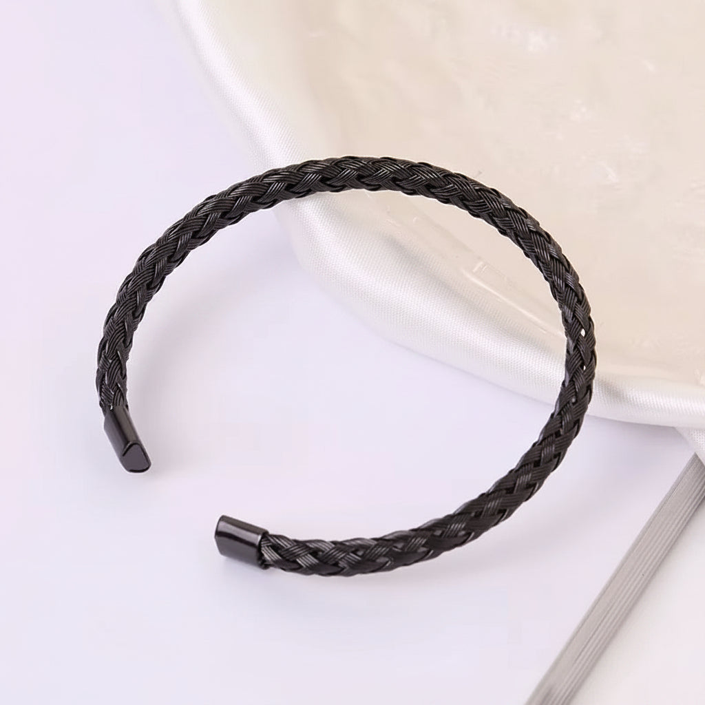 Black braided bracelet on a white surface with text in the background
