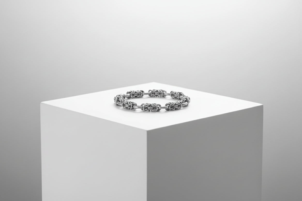 Silver bracelet on a white pedestal against a gray background