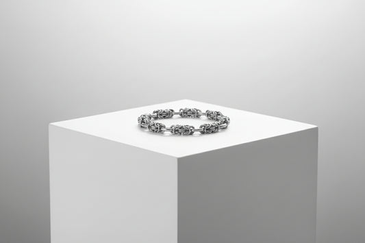 Silver bracelet on a white pedestal against a gray background