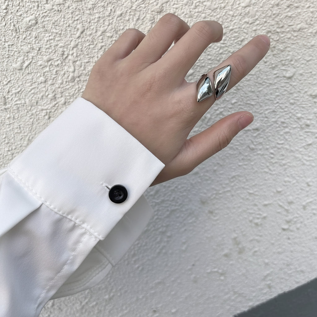 Ein versilberter Edelstahlring mit Dreiecksdesign, der am Finger getragen wird.