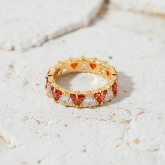 Goldring mit roten und klaren Edelsteinen auf einer grünen Marmoroberfläche