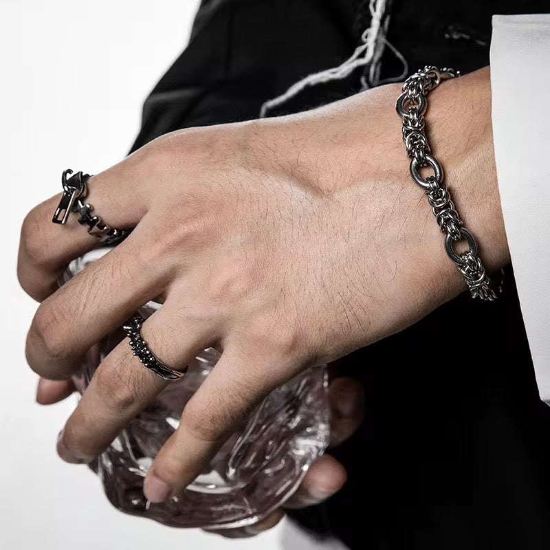 Close-up of a hand wearing multiple silver rings and a bracelet on a white background