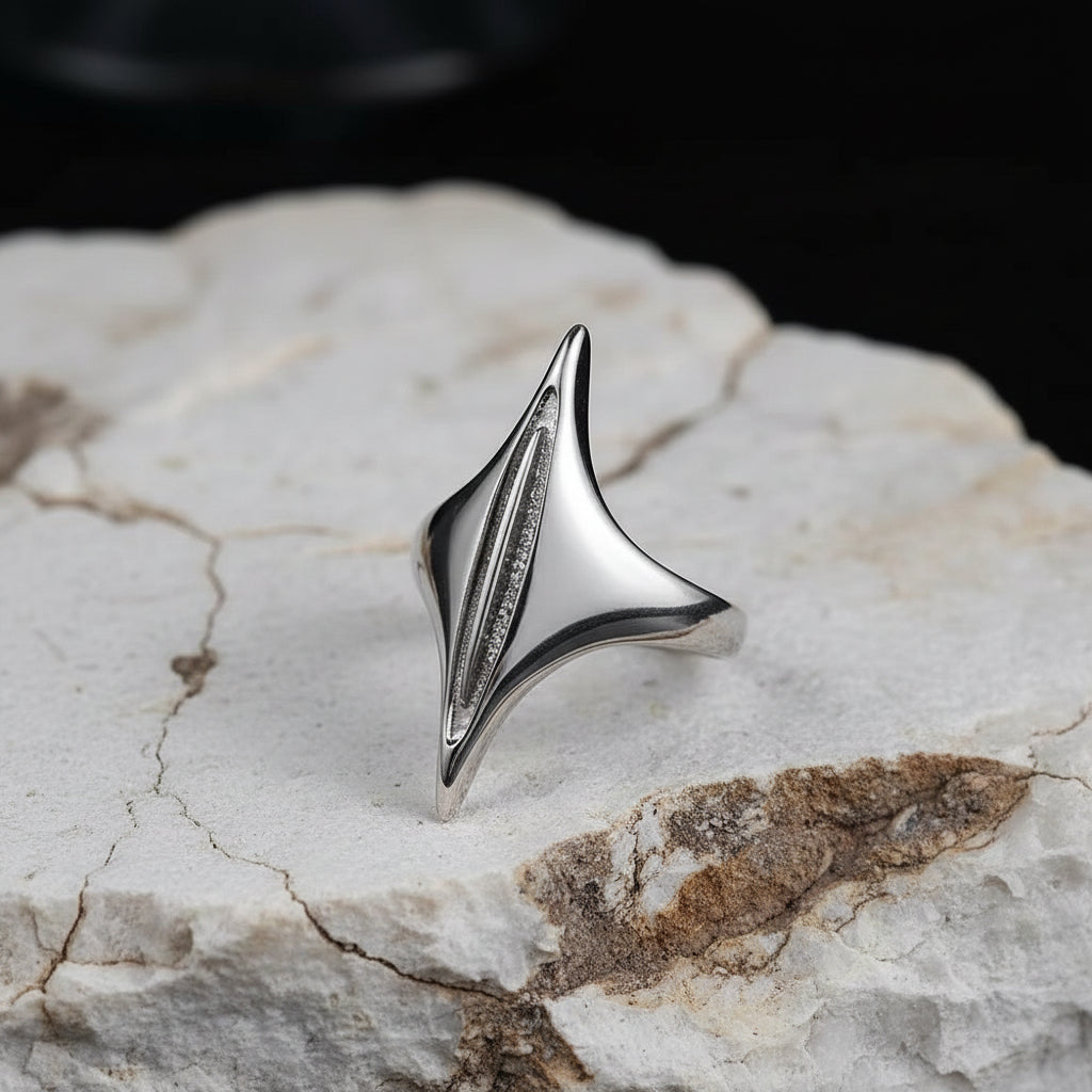 Silver spike-shaped ring on a dark textured surface