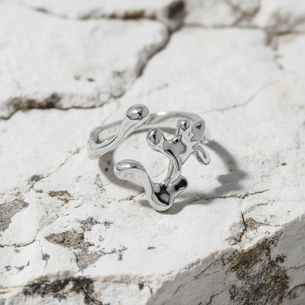 Ein rhodinierter Ring aus Sterlingsilber mit einem einzigartigen Design, möglicherweise interpretativ oder abstrakt, auf weißem Hintergrund.