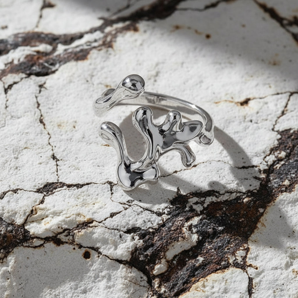 Ein rhodinierter Ring aus Sterlingsilber mit einem einzigartigen Design, möglicherweise interpretativ oder abstrakt, auf weißem Hintergrund.