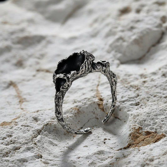 A sterling silver ring with a textured, corrosion-style design displayed against a dark background.