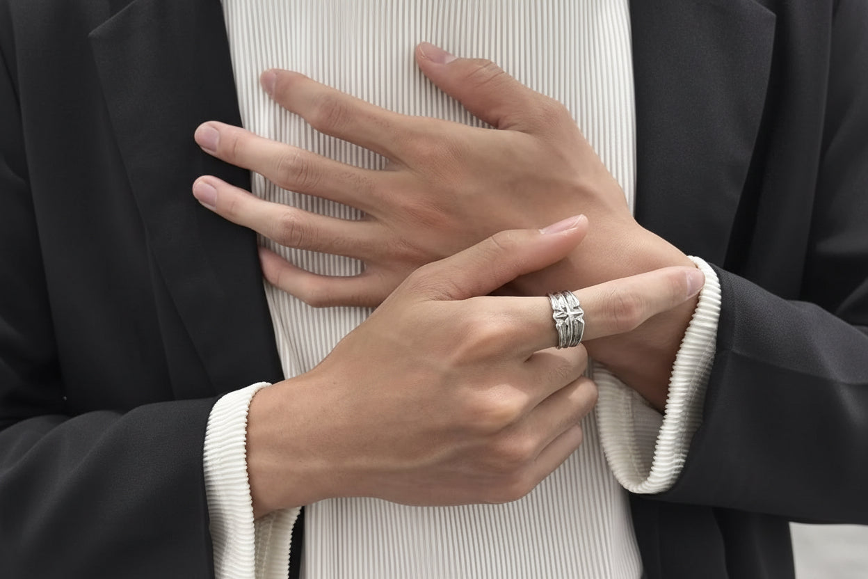 Close-up of hands with a silver ring on a neutral background