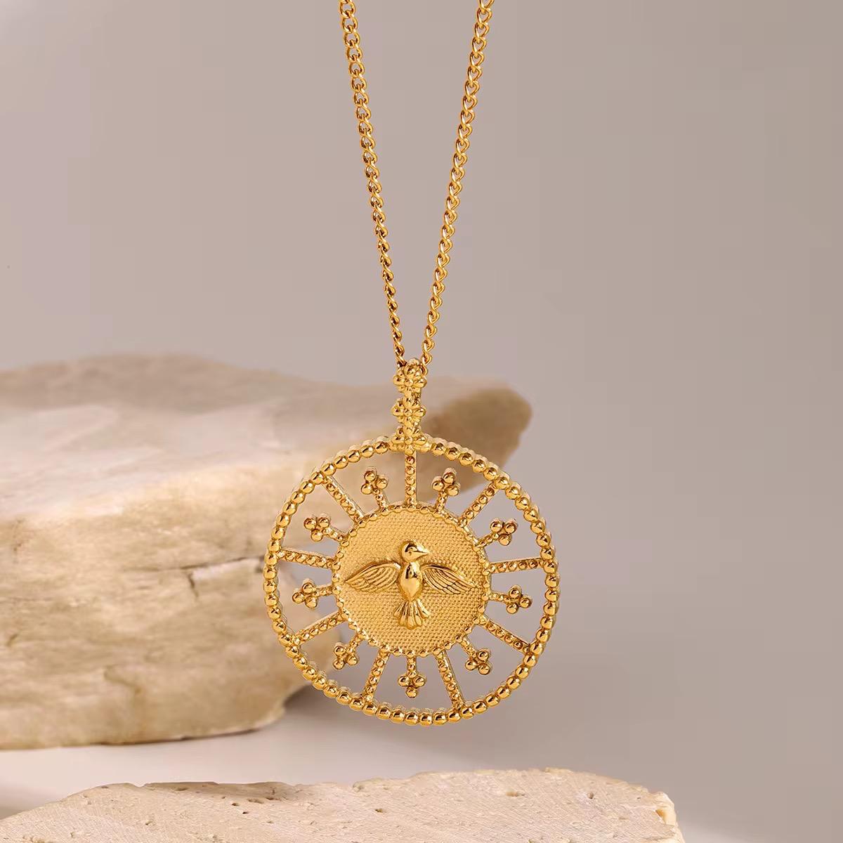 Goldkette mit einem runden Anhänger, der ein Taubenmotiv auf neutralem Hintergrund zeigt.