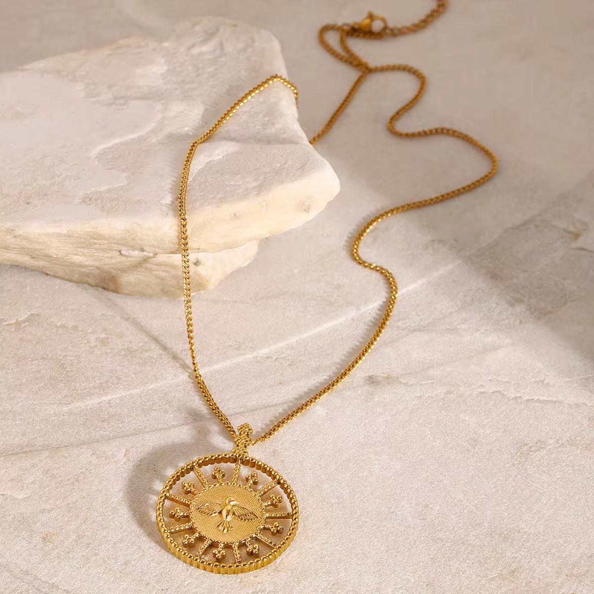 vergoldete halskette für Frauen mit rundem Anhänger auf heller Steinoberfläche