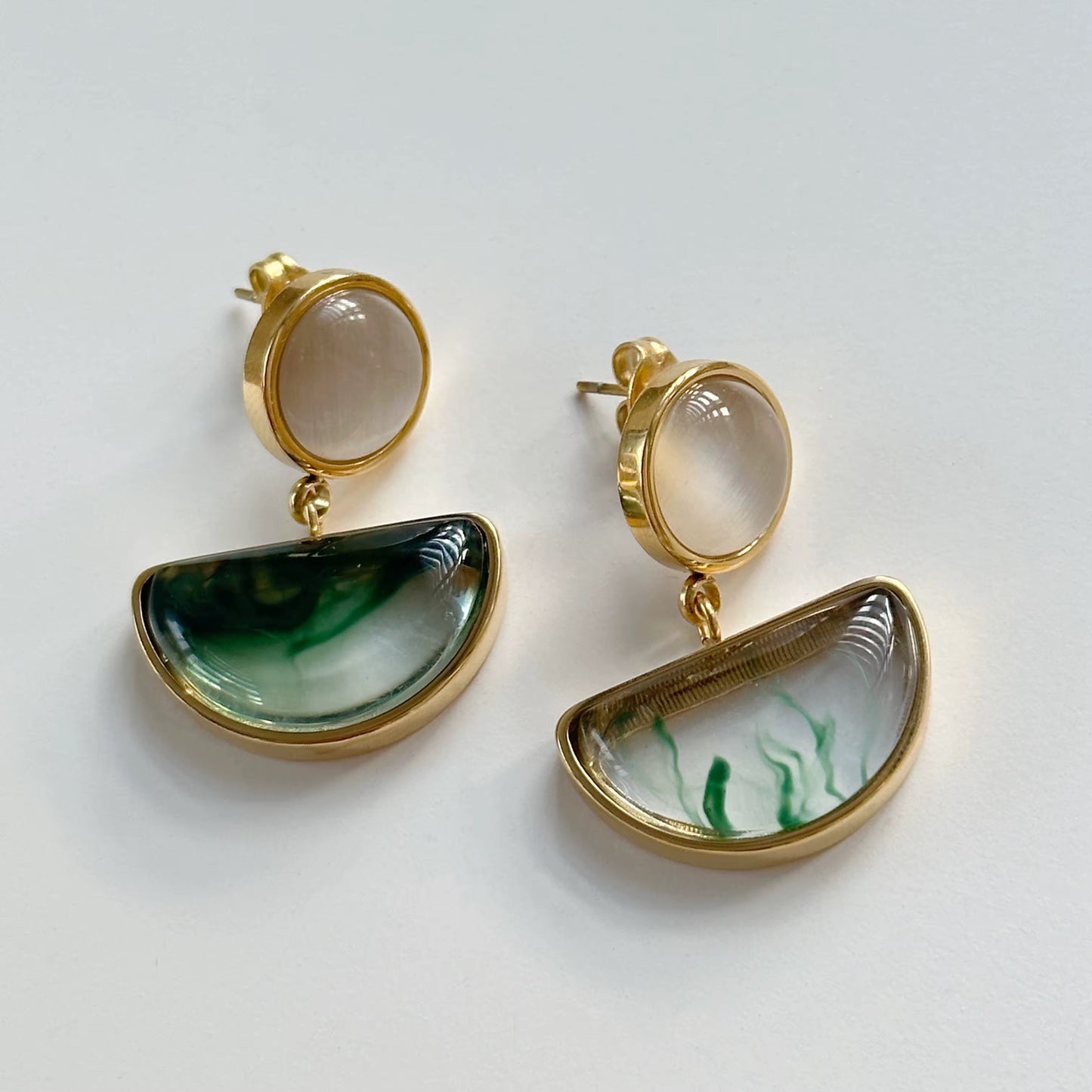 Nahaufnahme von vergoldeten Katzenaugen-Ohrringen mit Detailansicht.