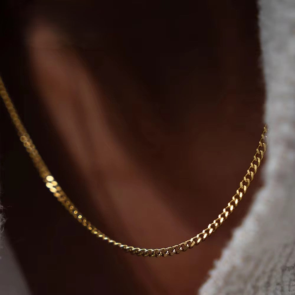 Nahaufnahme einer vergoldeten Edelstahlkette an einer Person, die die Details der Kette vor einem unscharfen Hintergrund zeigt.