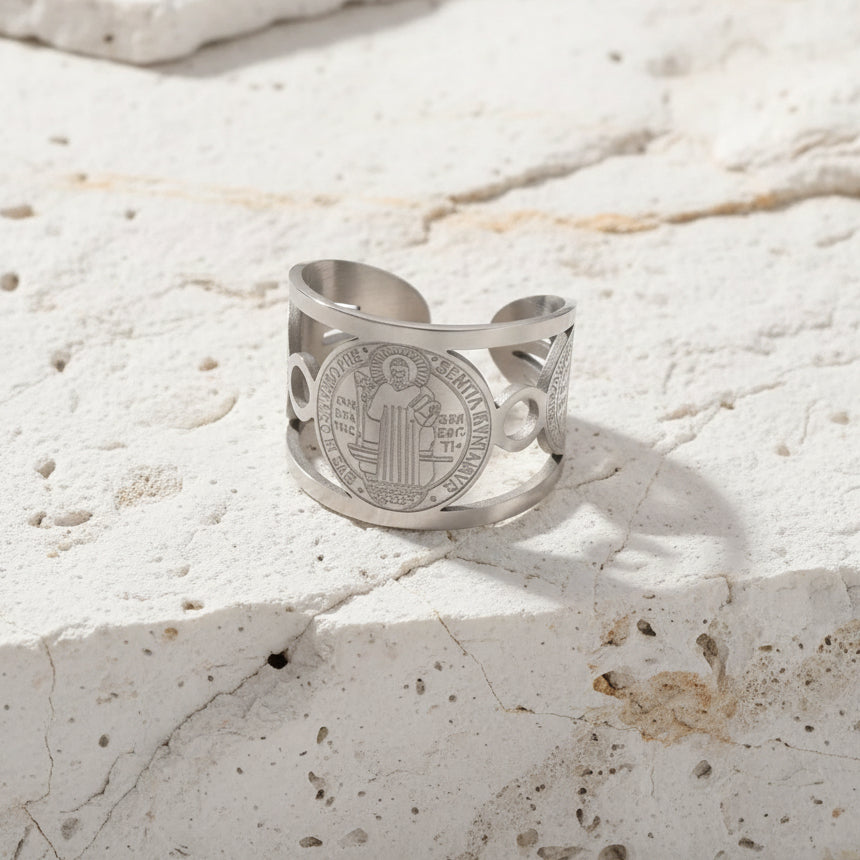 Ein Ring aus 18 Karat vergoldetem Edelstahl mit verstellbarem Band, präsentiert auf einem rosa Hintergrund mit einer Blume.