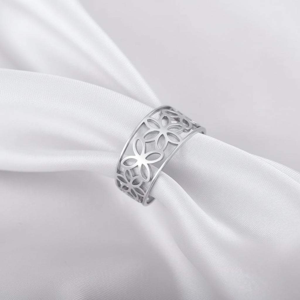 Ein Ring aus 18 Karat vergoldetem Edelstahl mit einem hohlen Blumenmotiv, präsentiert auf einem Satinstoff.