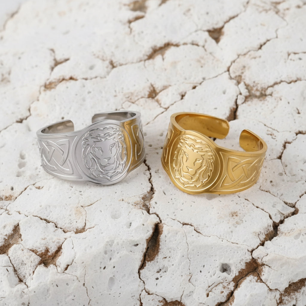 Zwei Ringe, einer mit Silberbeschichtung und der andere mit Goldbeschichtung, mit nordischen Löwenmotiven, präsentiert auf einer Satinoberfläche.