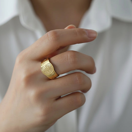 Die Hand einer Person, die einen vergoldeten Edelstahlring mit einem geprägten Löwenmotiv auf der Oberseite trägt.