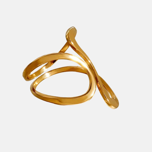 Ein vergoldeter Edelstahlring mit abstraktem Design, präsentiert auf einem Stein.