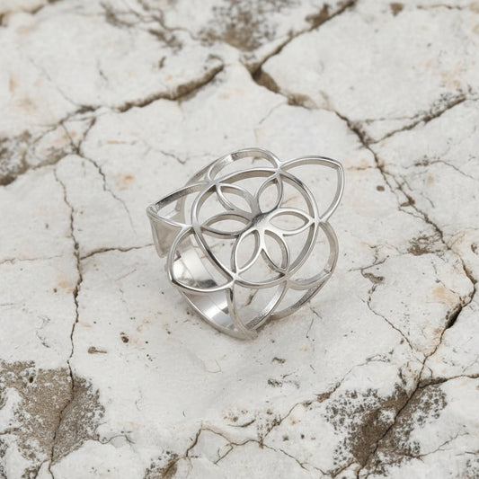 Ein 18 Karat vergoldeter Edelstahlring mit Blumenmuster, präsentiert auf einem rosa Satintuch.