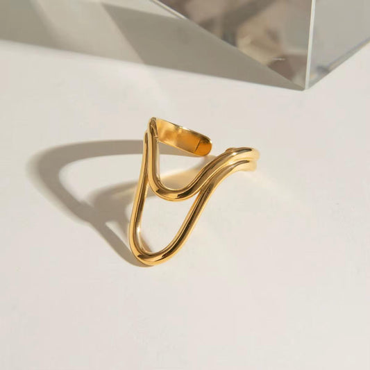 Goldring mit wellenförmigem Design auf hellem Hintergrund