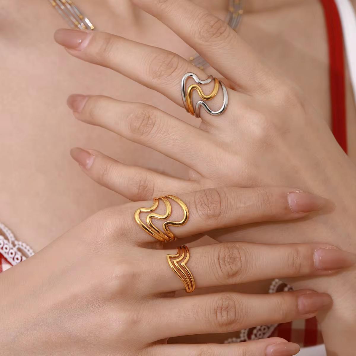 Nahaufnahme einer Hand mit zwei goldenen Ringen vor rotem Hintergrund