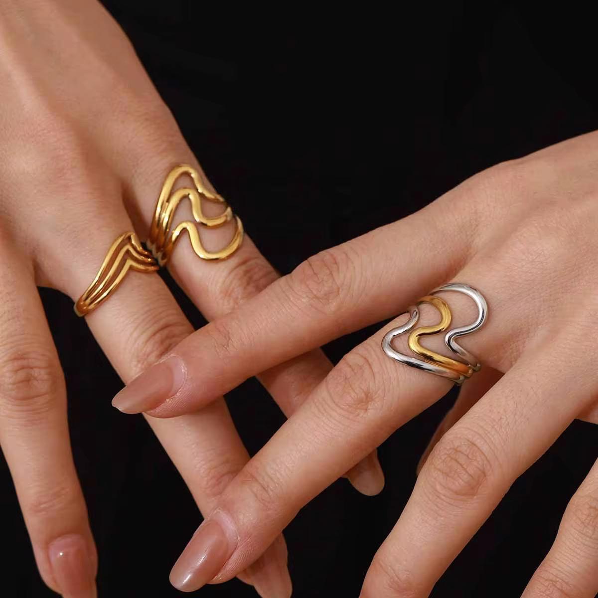 Nahaufnahme einer Hand mit zwei goldenen Ringen vor rotem Hintergrund