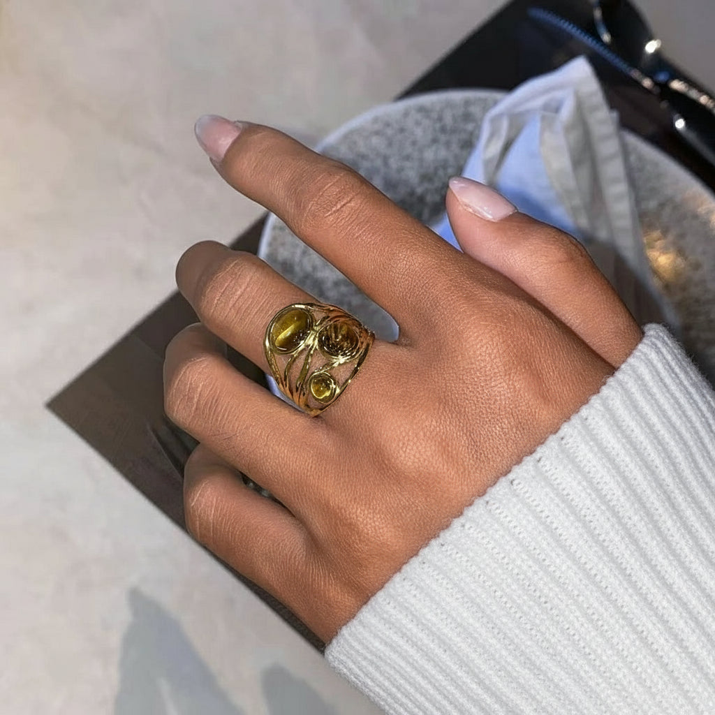 Hand mit einem goldenen Ring mit einem großen Edelstein, unscharfer Hintergrund