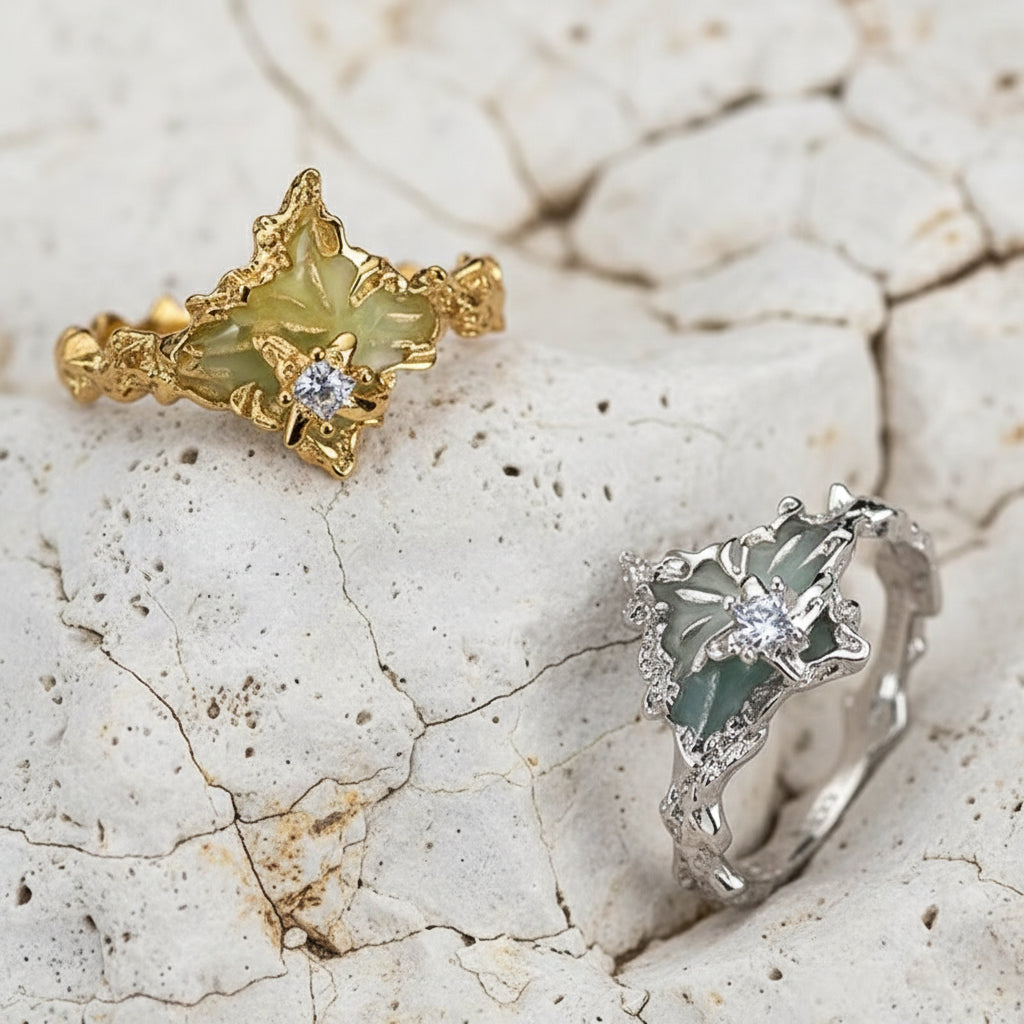 Zwei Ringe, einer aus Gold und einer aus Silber, auf einer strukturierten beigen Oberfläche.