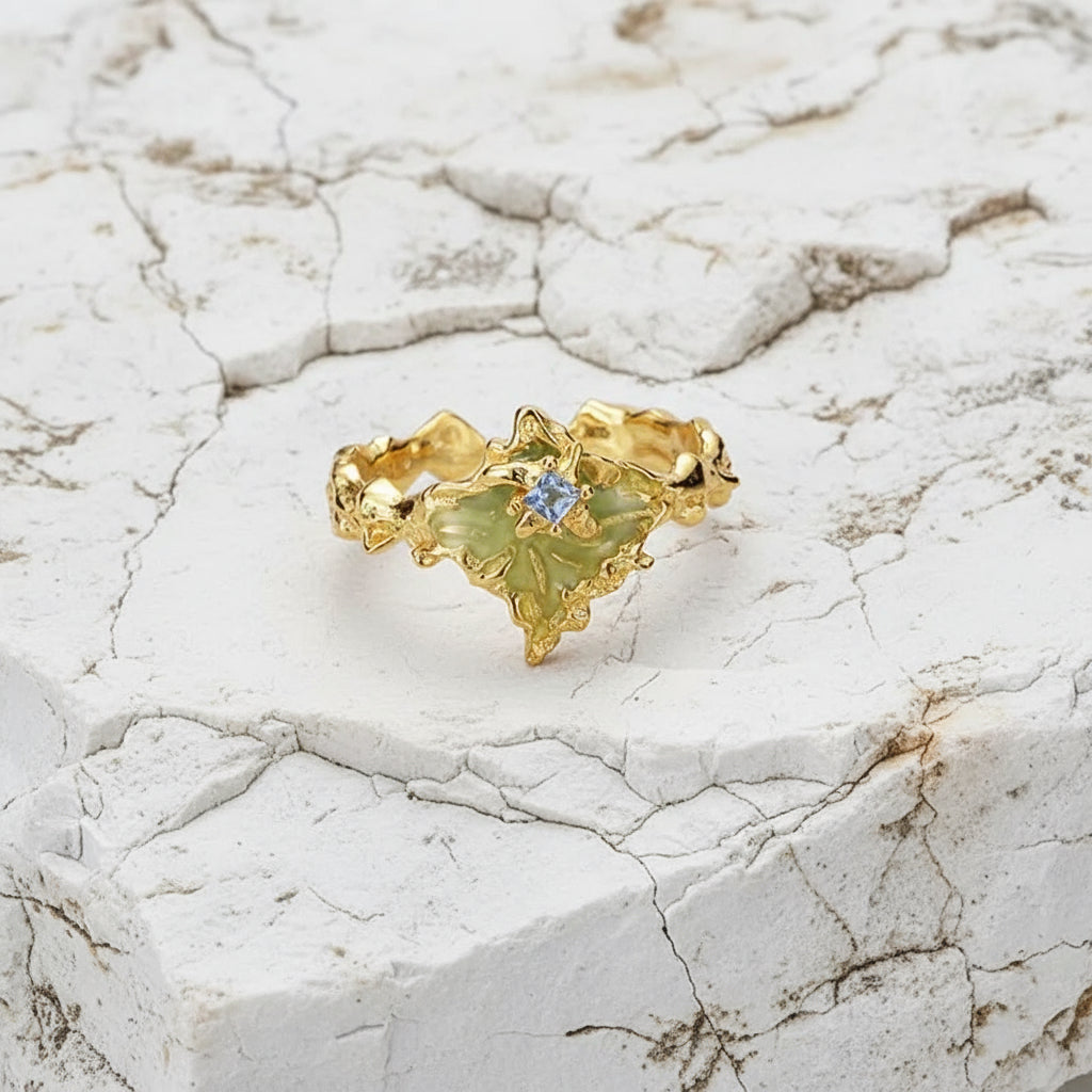 Ein vergoldeter Silberring mit Tropfenmuster und Zirkonsteinverzierung, dargestellt vor weißem Hintergrund.