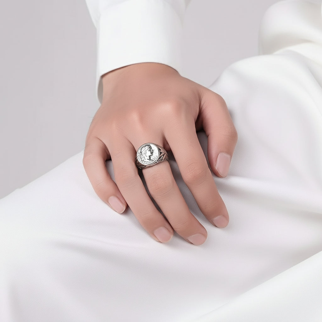 Ein versilberter Edelstahlring mit einem detaillierten Design und einer geprägten Caesar-Münze als Mittelstück, präsentiert auf weißem Untergrund.