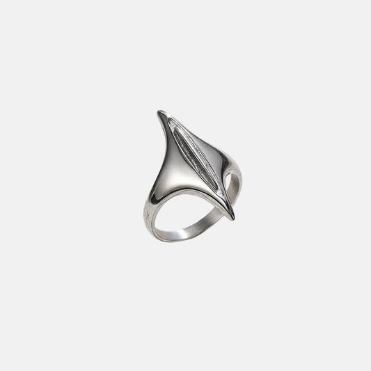 Ein versilberter Edelstahlring mit geometrischem Design, präsentiert auf einer strukturierten grauen Oberfläche.