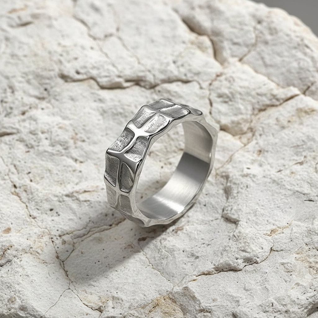 Ein versilberter Unisex-Ring aus Edelstahl mit einem melierten Design, präsentiert auf einer reflektierenden Oberfläche.